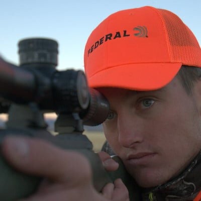 Hunter looking through binoculars on the prairie