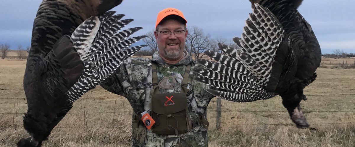 Hunter holding up two dead turkeys