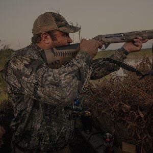 hunter aiming shotgun with a shotshell being ejected while outside