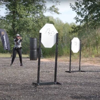 Krystal standing behind a few target while aiming a handgun