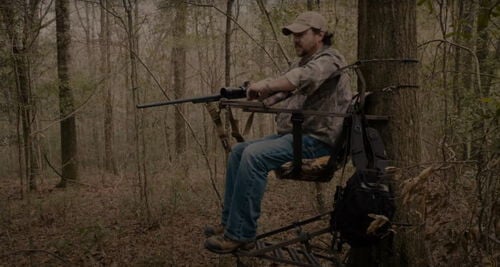 Jim Gilliland sitting on a climber holding a rifle