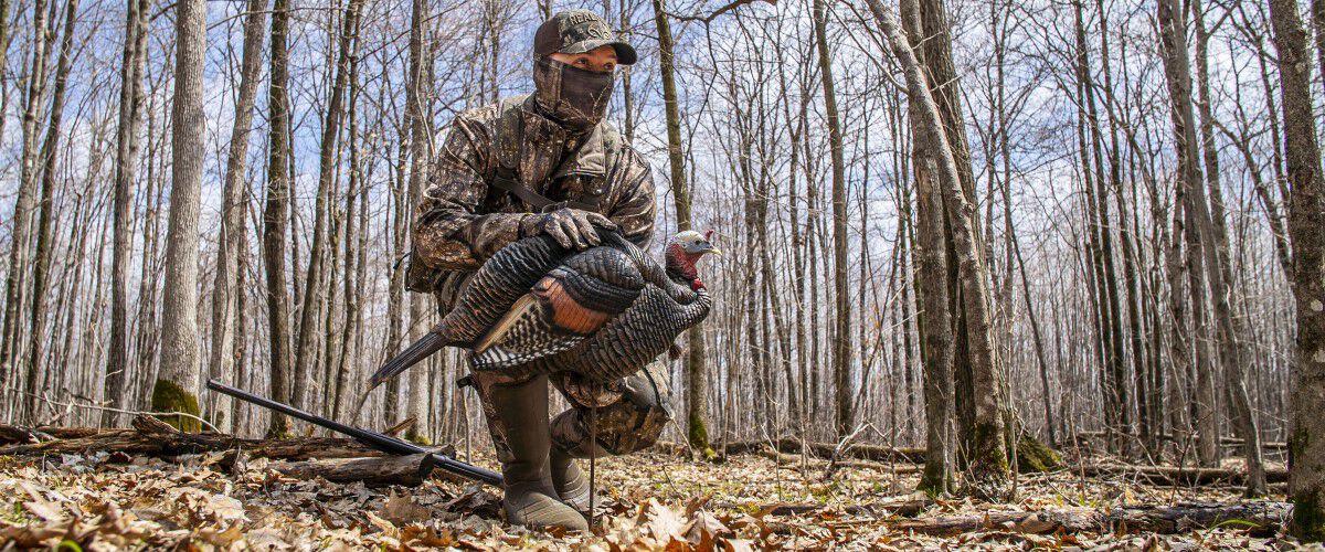 hunter squatting down with holding a shotgun