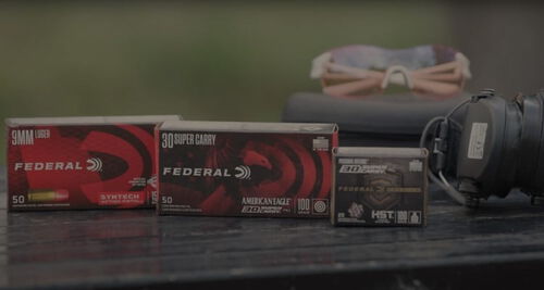 ear protection, eye protection, and boxes of Syntech Action Pistol, American Eagle 30 Super Carry, and HST on a table
