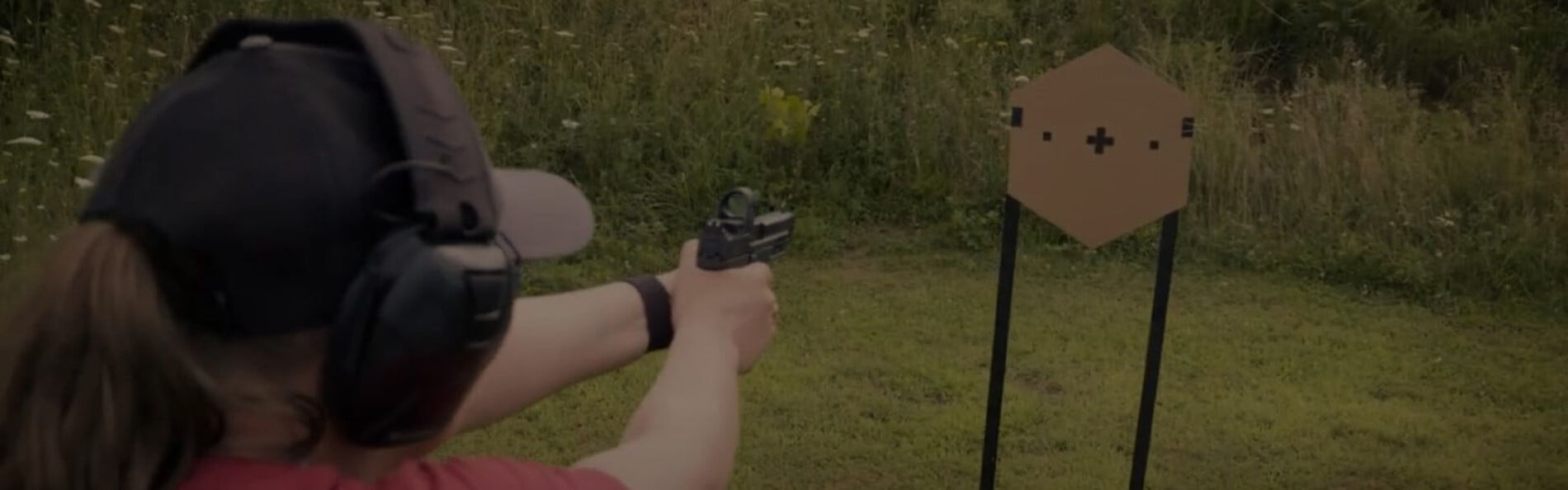 Julie Golob aiming a handgun at a target outside