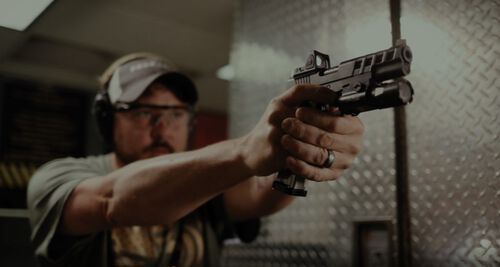 Jim Gilliland Looking down a handgun at an indoor range