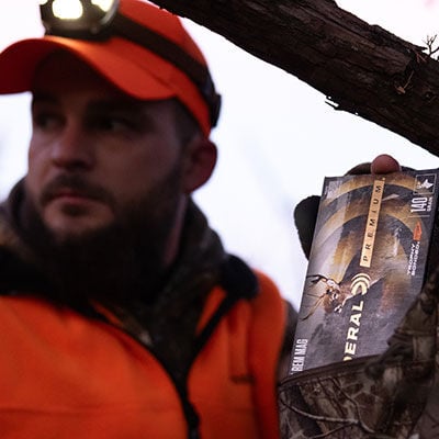 hunter grabbing box of Trophy Bonded Tip out of a backpack