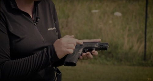 Julie Golob examining her pistol in her hand