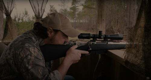 Jim Gilliland looking down a rifle scope while in a box stand
