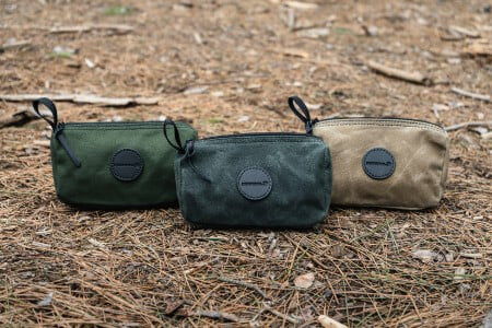 Khaki, Olive and Olive Drab Grab-N-Go bags sitting on the ground covered in pine needles