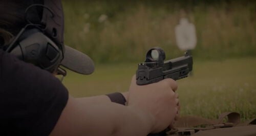 Julie Golob laying on the ground aiming a handgun