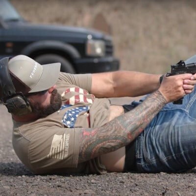 Josh aiming his handgun while laying on the ground