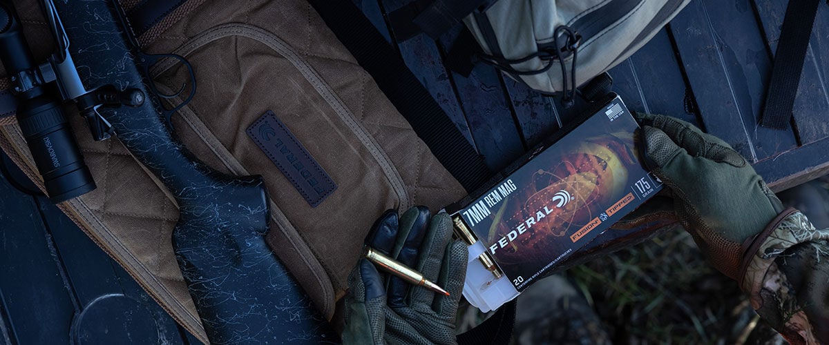 person holding Fusion Tipped Rifle box and cartridge