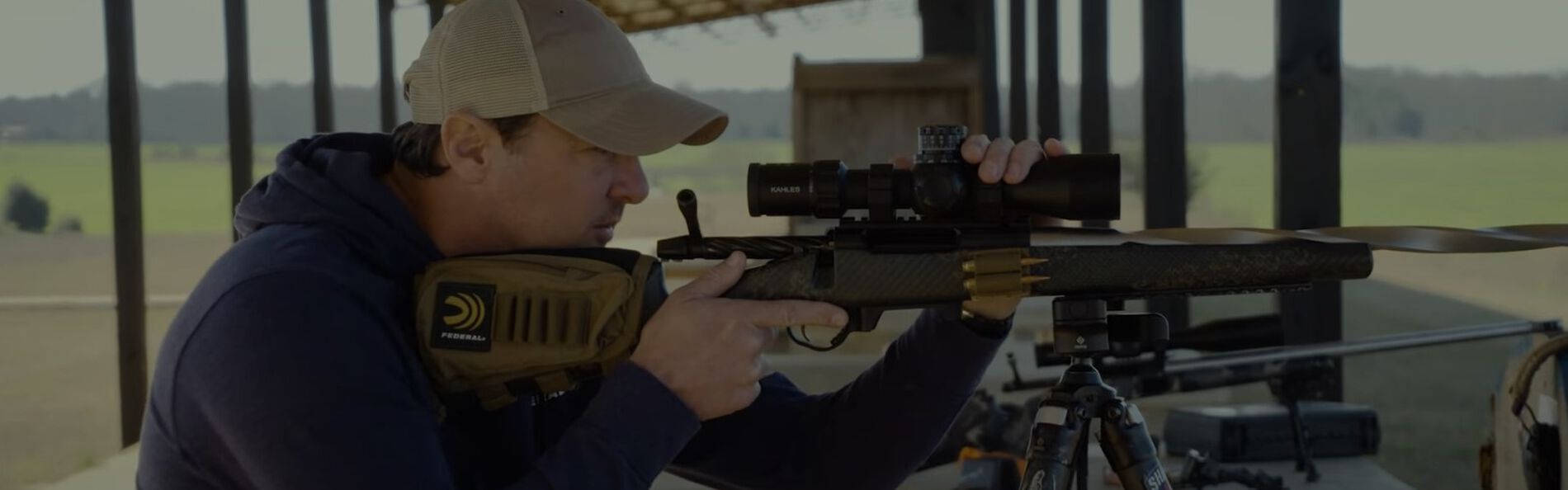 Jim Gilliland looking down the scope of a rifle resting on a tri-pod