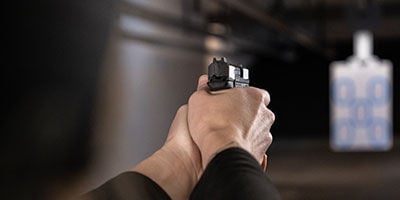 handgun being aiming toward a target at in indoor range