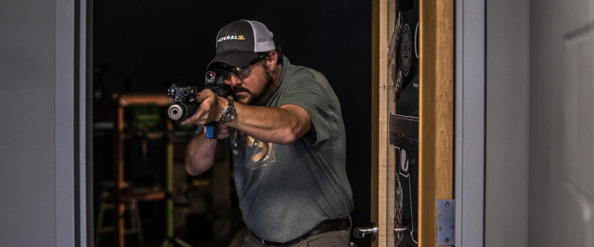 Man pointing rifle outside of door