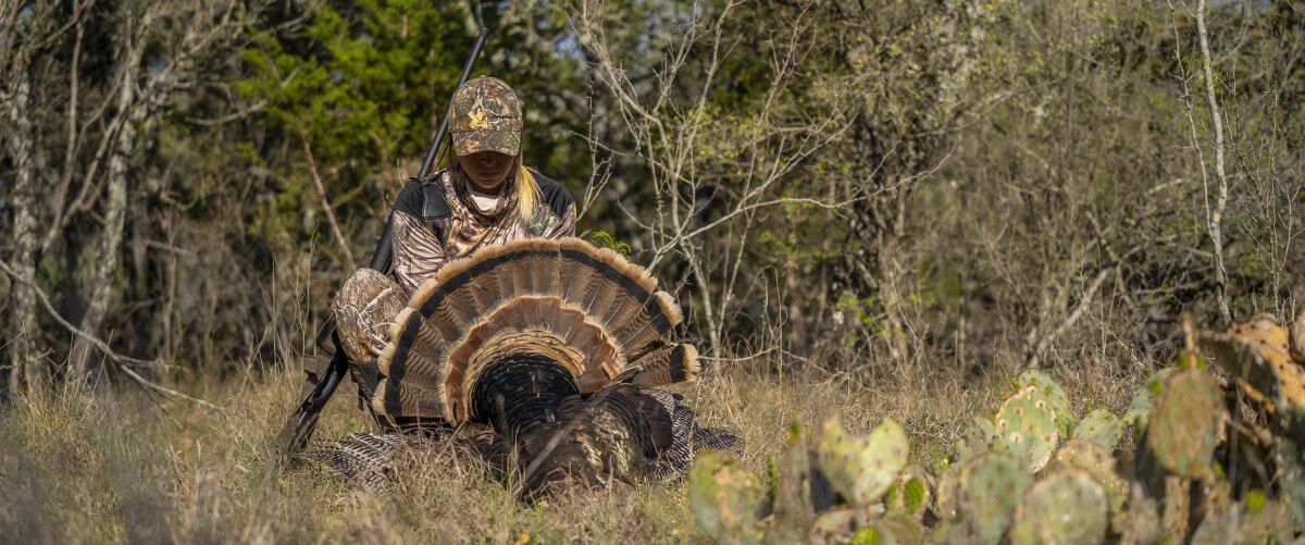 female hunter fanning the tail of a downed turkey