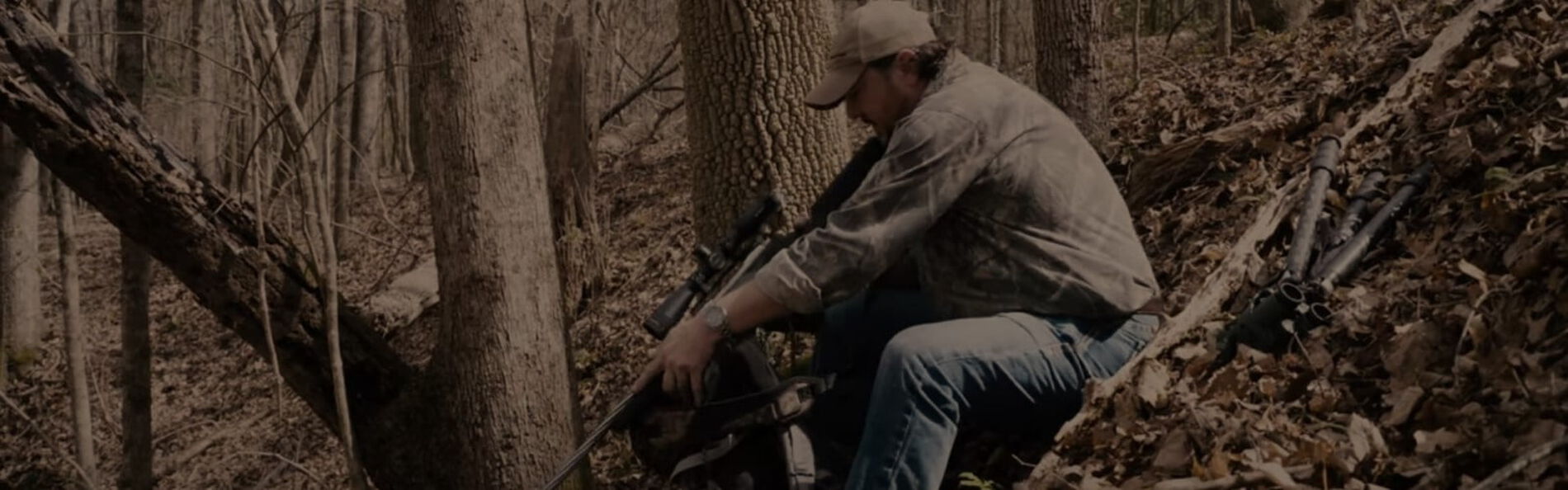 Jim Gilliland looking down the rifle scope resting on a backpack