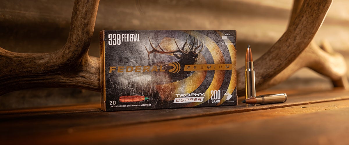 Federal Trophy Copper 338 Federal box on a table with an antler and cartridges
