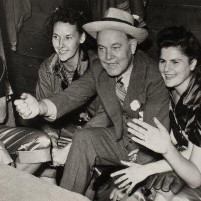 Charles Horn sitting with some female softball players in the dugout