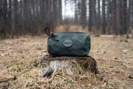 Olive Grab-N-Go Bag sitting on a tree stump in a wooded area