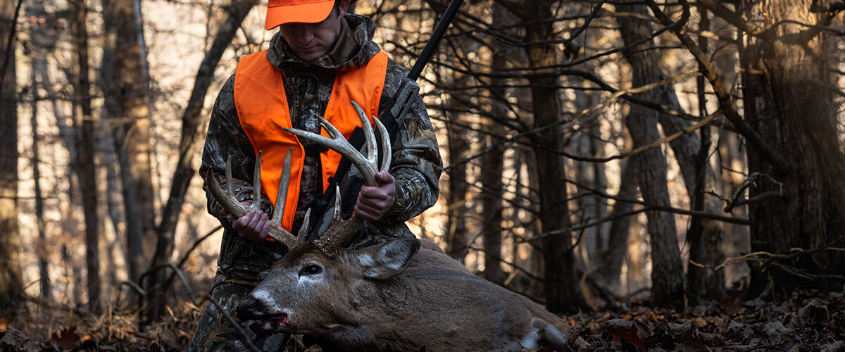 hunter loading up a deer by the antlers