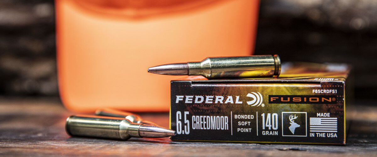 Federal Fusion cartridges and packaging laying on a table in front of a blurry orange hunter hat