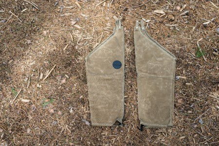Chaps laying on the ground surrounded by pine needles