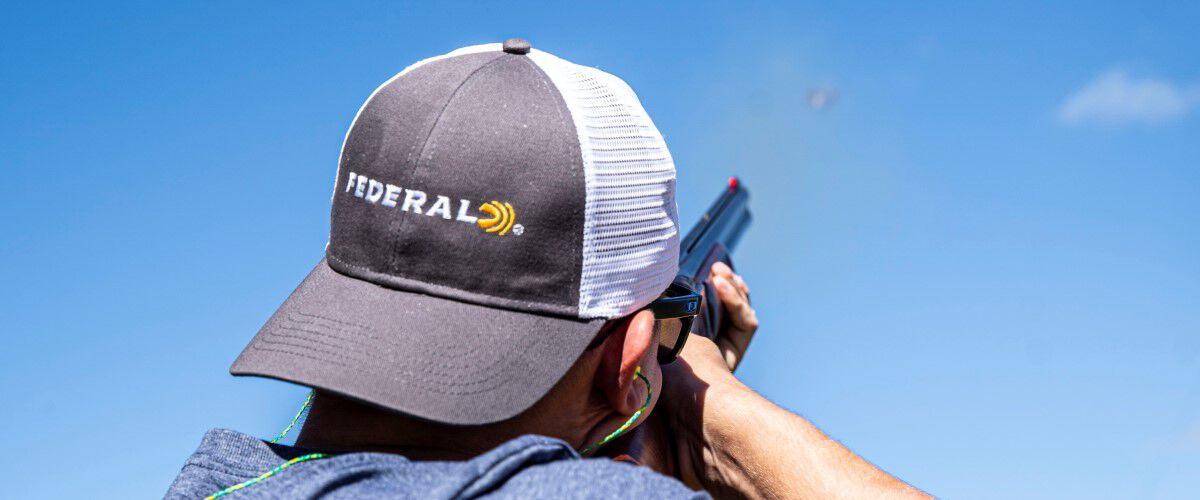 man shooting with a Federal trucker hat on