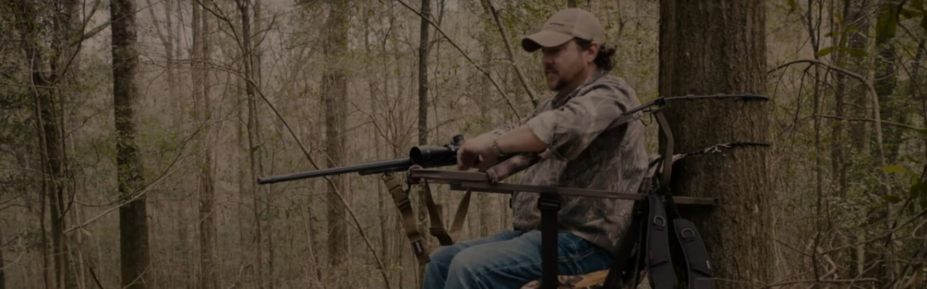 Jim Gilliland sitting on a climber holding a rifle