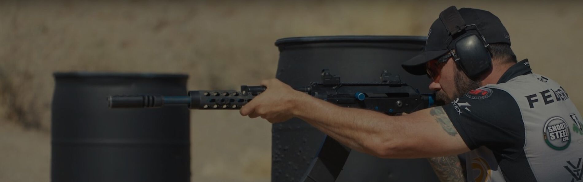 Josh Froelich shooting Shotgun from behind a barrel outside