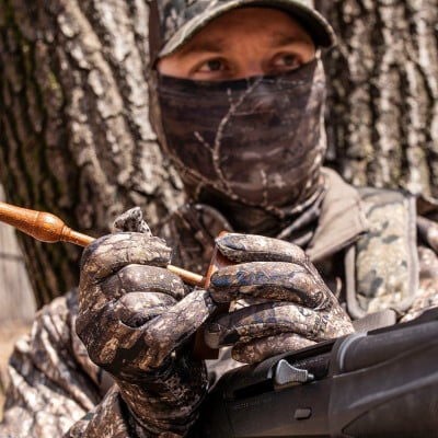 hunter using a turkey call in the woods