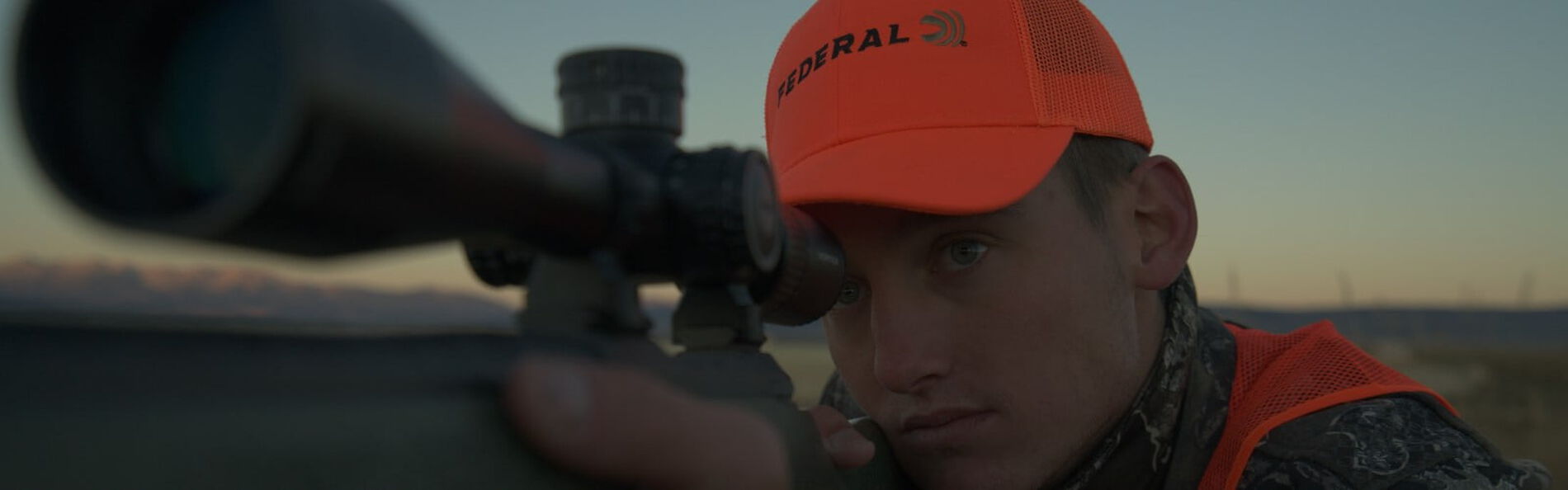 Hunter looking through binoculars on the prairie