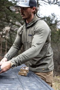 male wearing the Helio Hoody standing at a truck tailgate with Federal Premium ammunition boxes