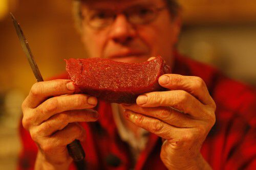 man holding up deer tenderloin piece