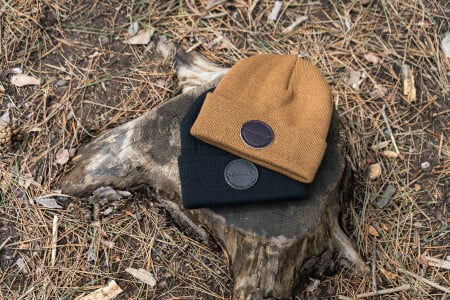 Black and Brown Beanies on a tree stump in a wooded area