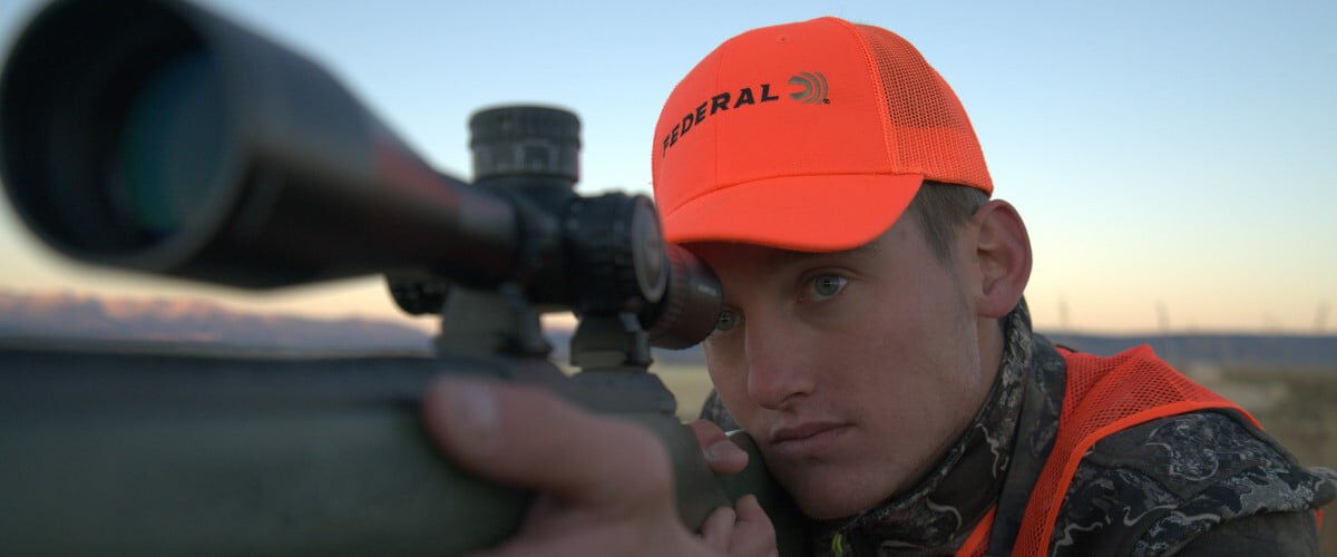 Hunter looking through binoculars on the prairie