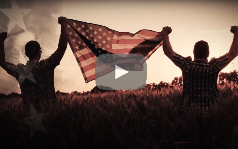 two people holding an American flag while walking away from the camera