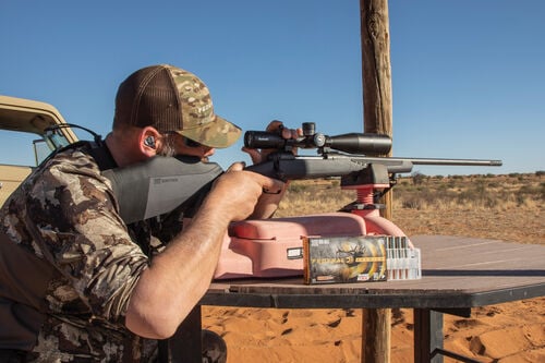 man adjusting rifle scope