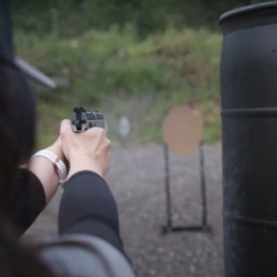 Krystal Shooting around a large black barrel