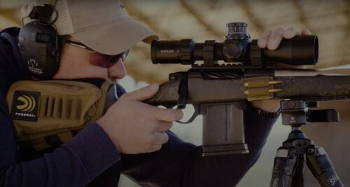 man looking down the rifle scope at a range