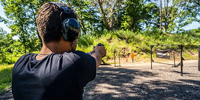 shooter aiming handgun at an outdoor range