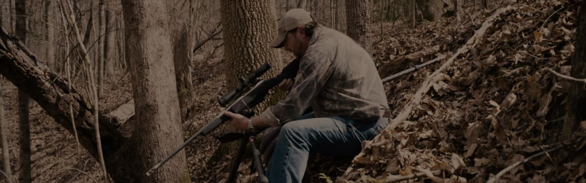 Jim Gilliland standing by a rifle on a tripod