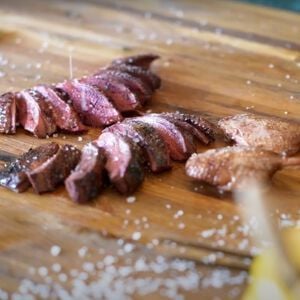 honey roasted waterfowl cut into pieces on a cutting board