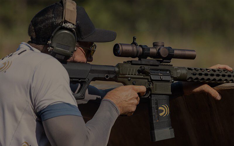 shooter resting rifle and looking down the scope
