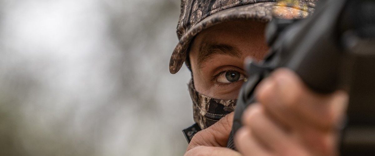 close-up of a hunter looking down the iron sights of a rifle