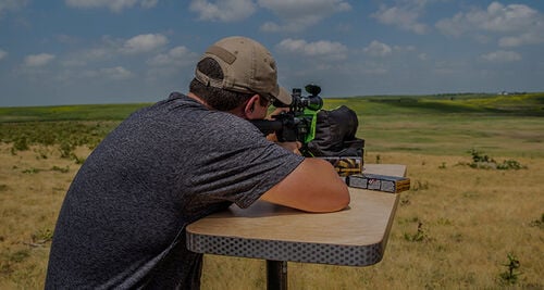 Man looking down a rifle scope