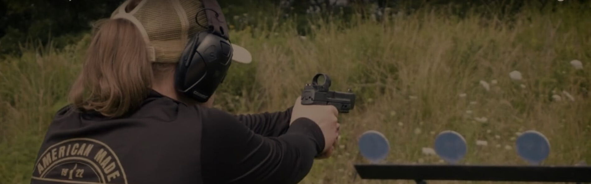 Julie Golob aiming handgun at multiple targets outside