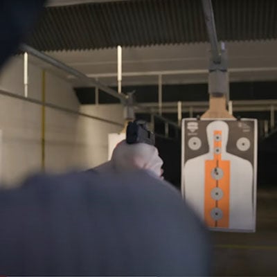 shooter aiming handgun at a target in an indoor range