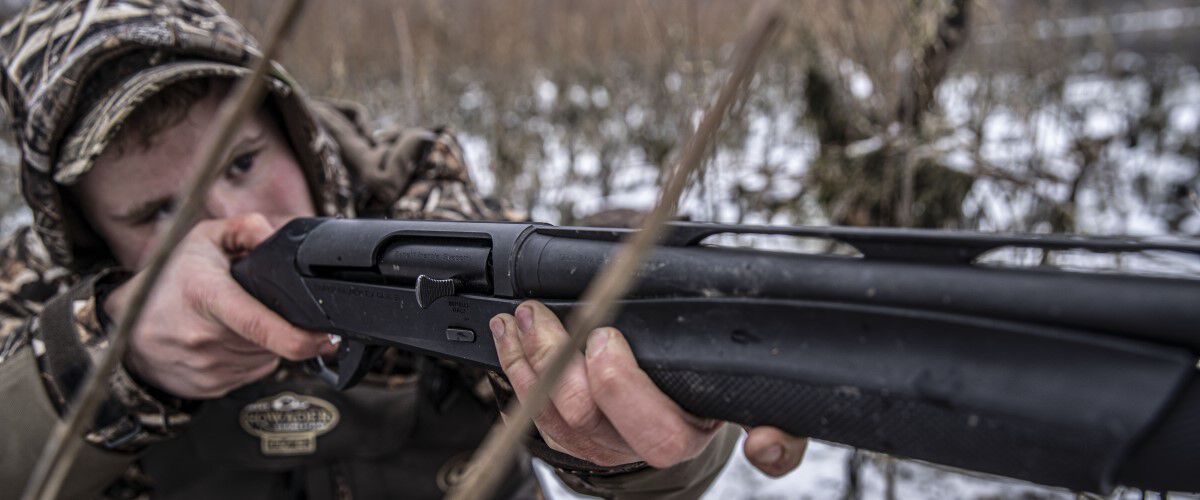 hunter looking down the sites of a shotgun