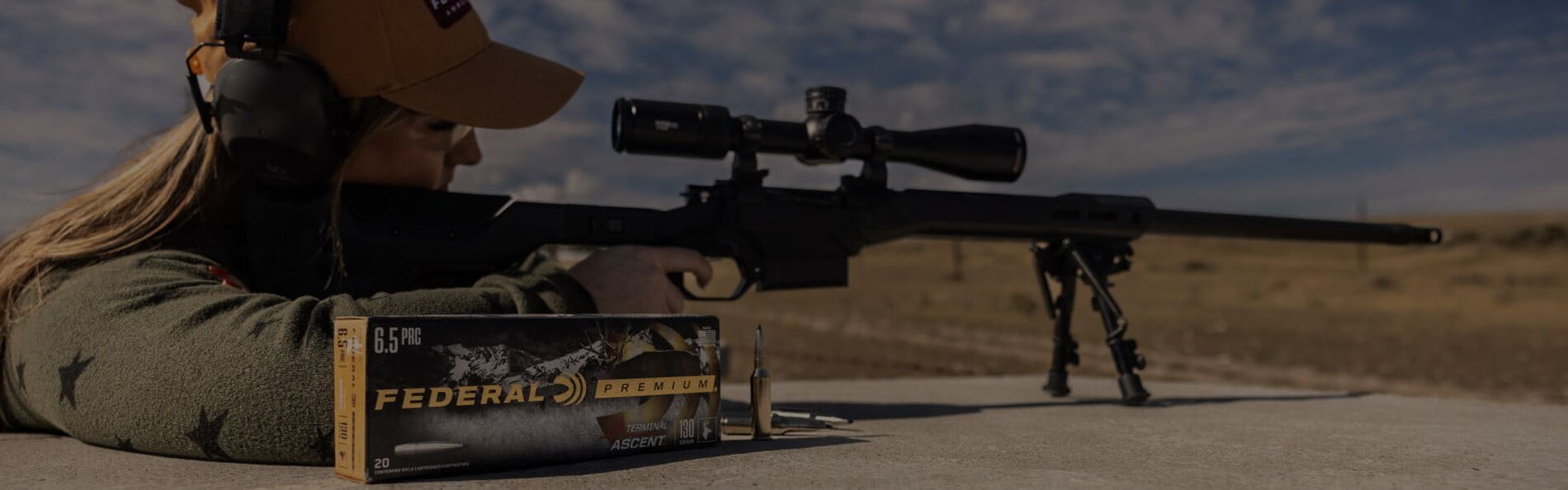 shooter looking through a rifle scope with a box of Terminal Ascent on a table